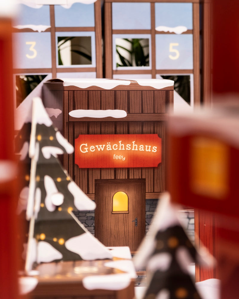 Zwischen verschneiten Bäumen steht ein gemütliches Holzgebäude mit der Aufschrift 